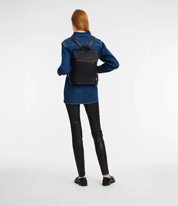 אישה לבושה ג'קט ג'ינס ומכנסי עור, לובשת תיק גב שחור CHOZEN, צילום על רקע לבן