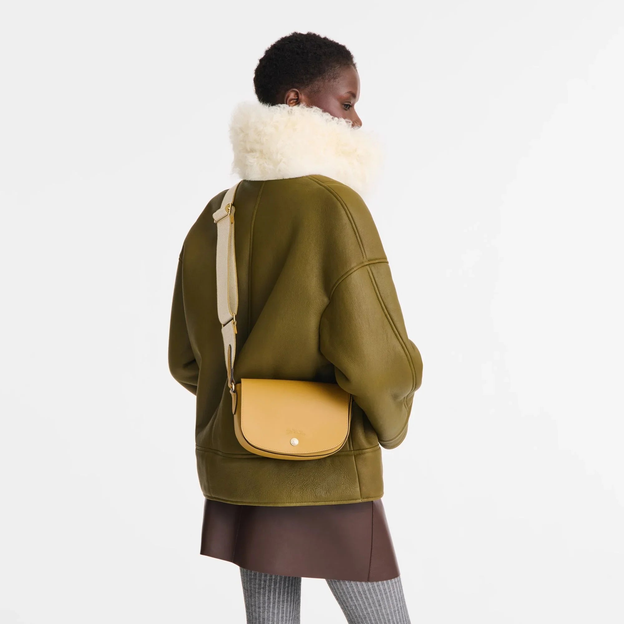 אישה עם מעיל ירוק בעל צווארון צמר, תיק עור צהוב, מגפונים אפורים, אופנה יוקרתית מ-CHOZEN