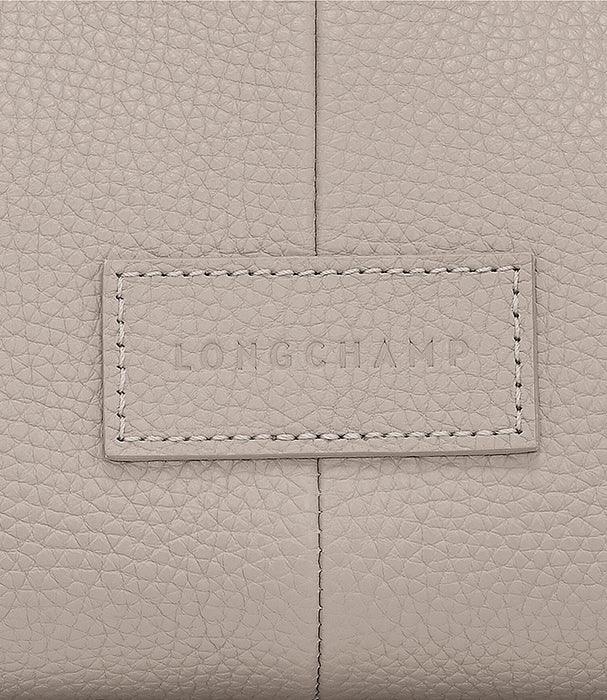 תקריב של תיק עור בצבע בז' עם תווית המותג LONGCHAMP, מבית CHOZEN יבואן רשמי