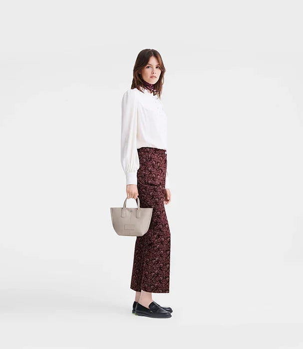 אישה בלבוש אלגנטי עם חולצה לבנה, מכנסיים מודפסים ותיק יד אופנתי, צ'וזן מותגים מובילים