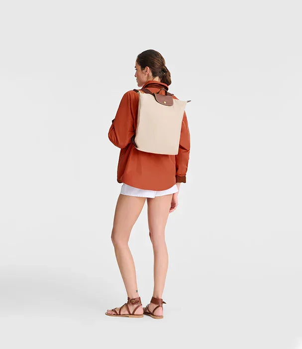אישה עם תיק גב בז', חולצה כתומה ומכנסיים קצרים, אופנה CHOZEN, צילום סטודיו