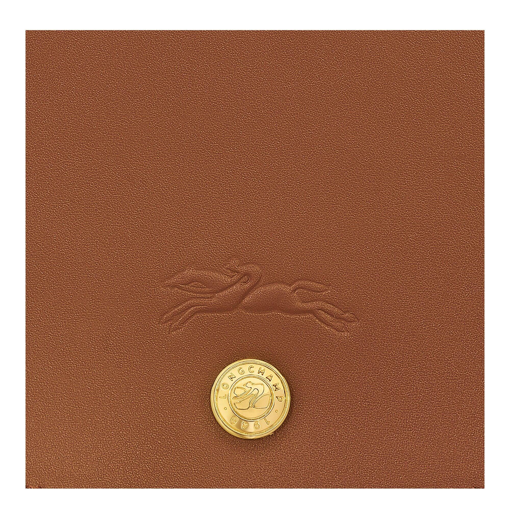 תקריב של עור חום עם סמל לונגשאמפ וכפתור זהב, מותג יוקרה ב-CHOZEN