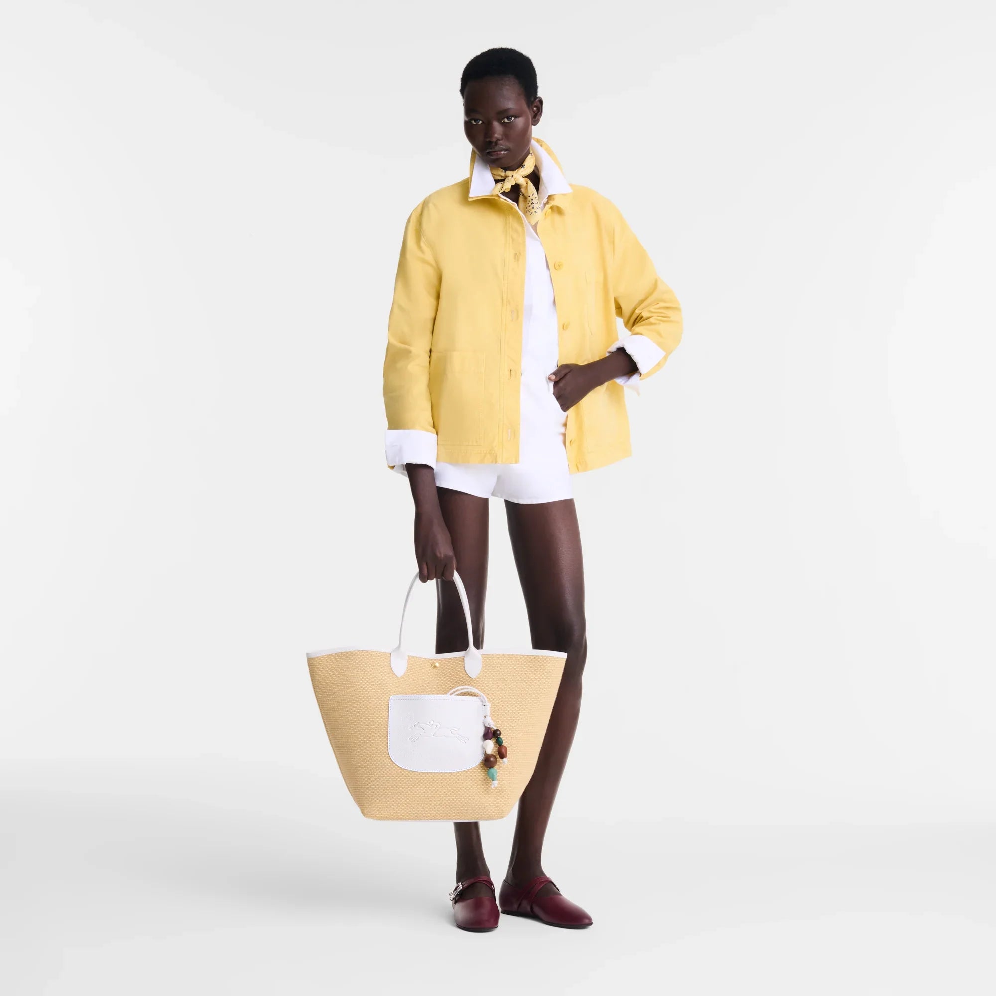 דוגמנית עם ז'קט צהוב, חולצה לבנה, תיק קש גדול ואביזרי אופנה, צולם ל-CHOZEN