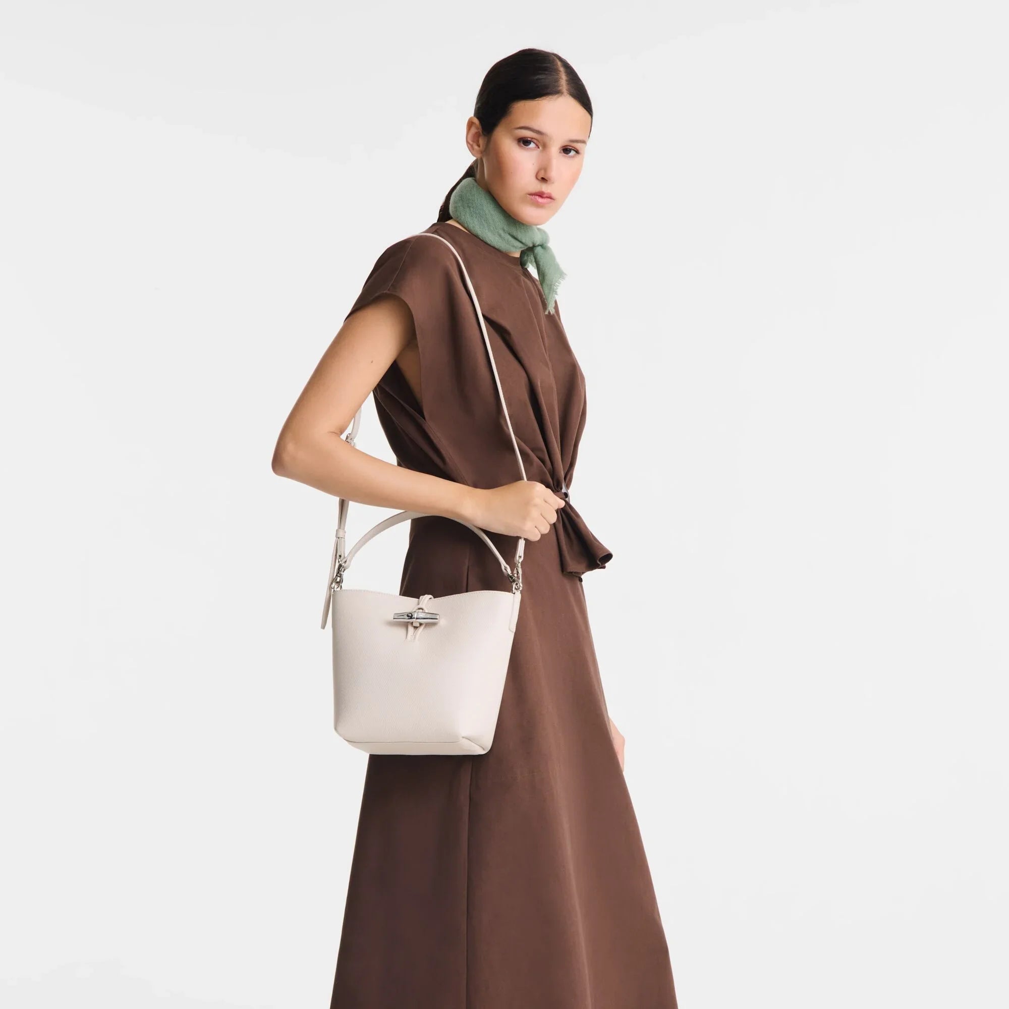 אישה עם שמלת חום וצעיף ירוק מציגה תיק מעוצב לבן, אופנה מ-CHOZEN קבוצת אלפא