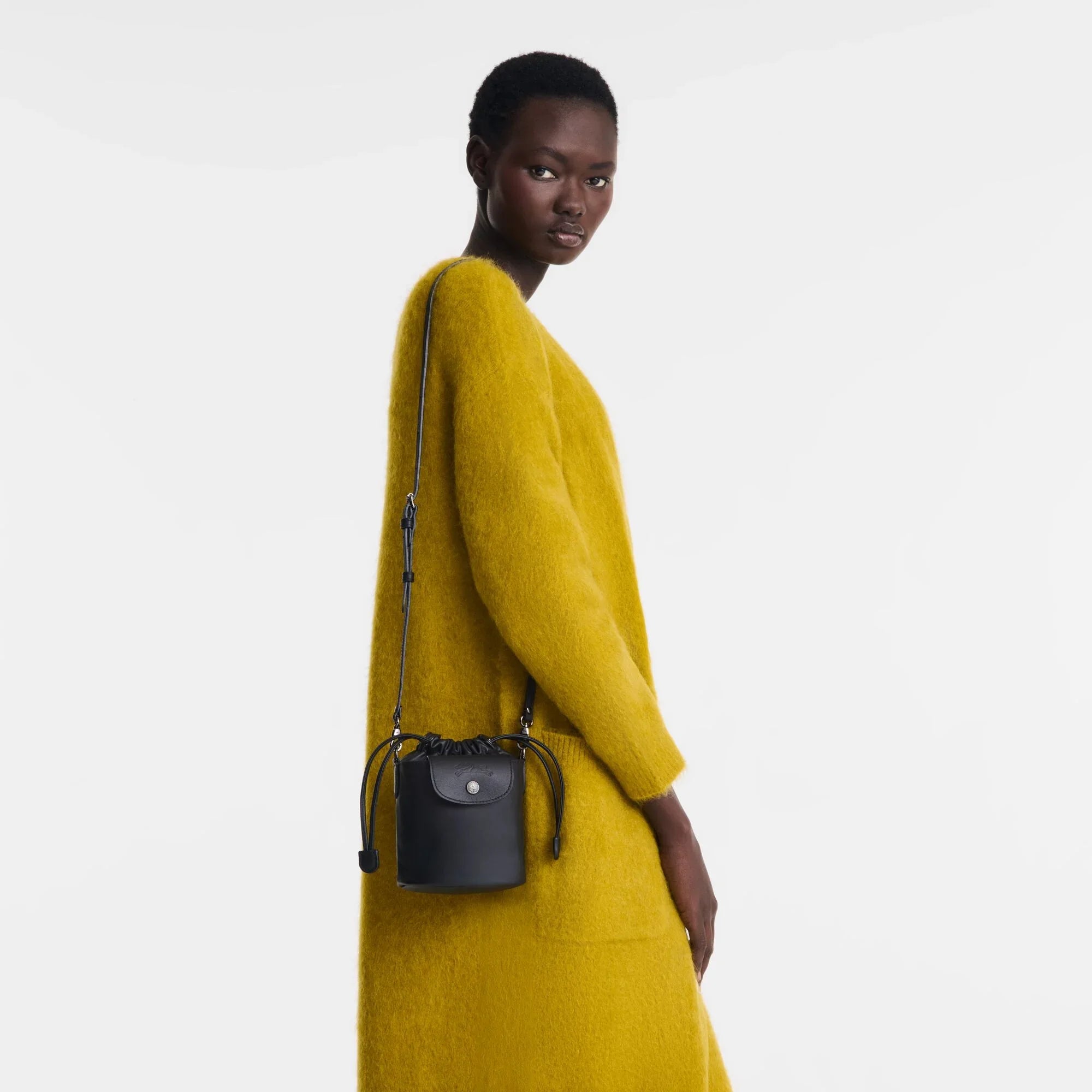 דוגמנית לובשת שמלה צהובה עם תיק צד שחור, אופנה יוקרתית מחנות CHOZEN