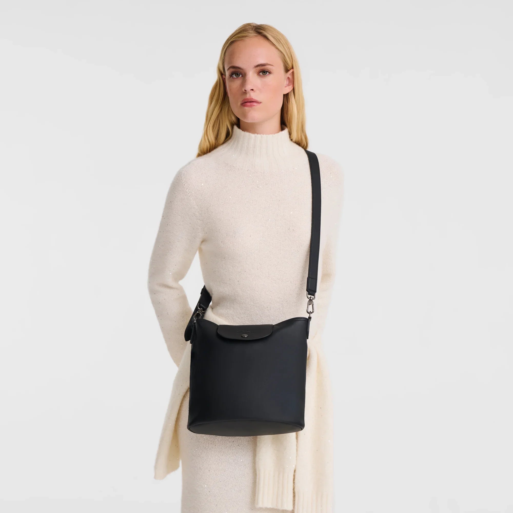 דוגמנית בלבוש סוודר שמנת מציגה תיק צד שחור אופנתי, מבית CHOZEN, רקע לבן נקי