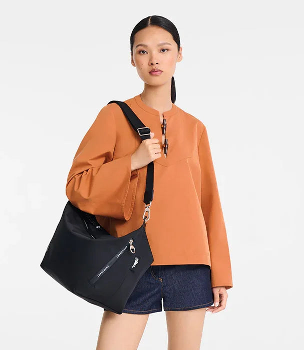 אישה עם חולצה כתומה ותיק צד שחור לקאוסט, אופנה ועיצוב מבית CHOZEN