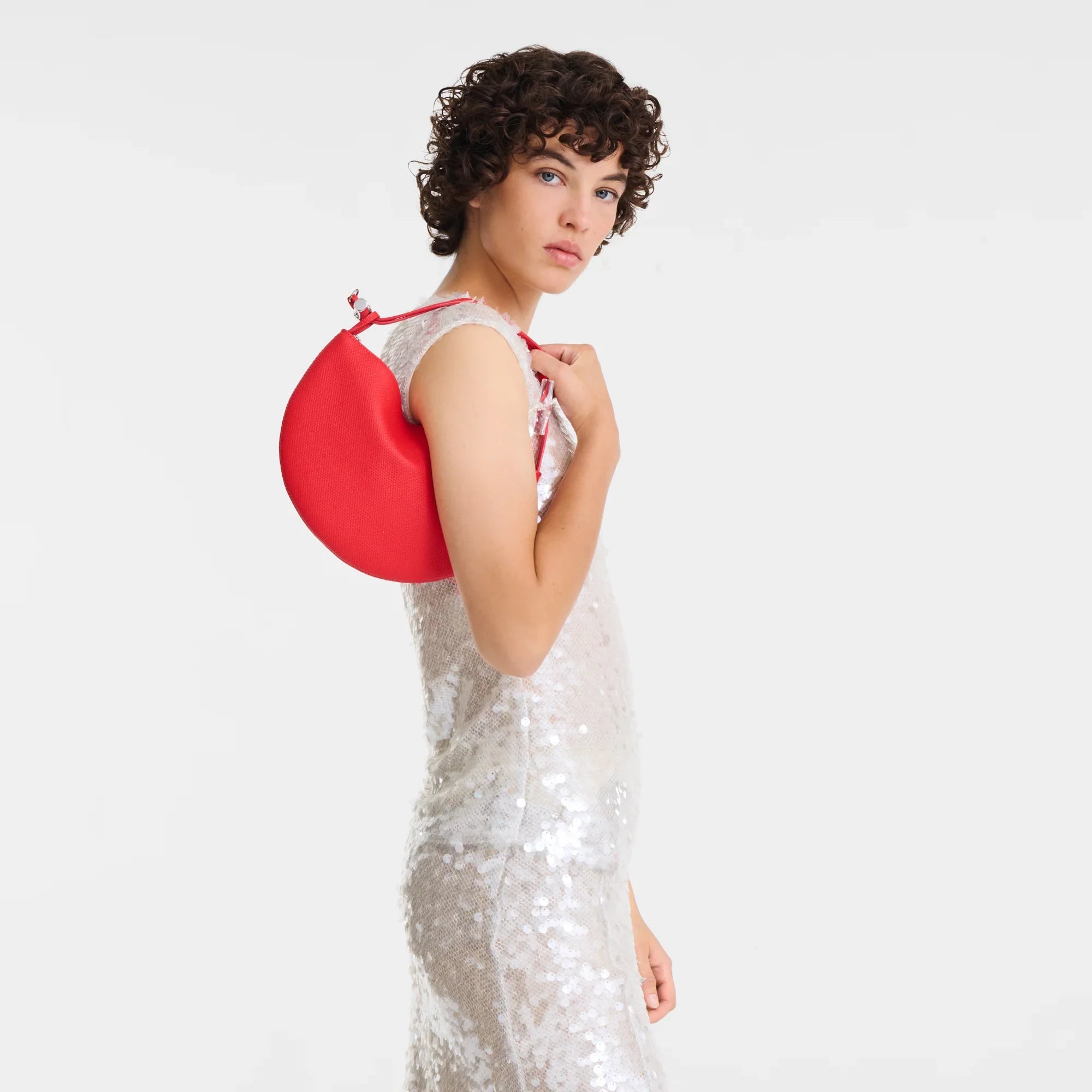 דוגמנית בשמלת פייטים כסופה נושאת תיק כתף אדום אופנתי מבית CHOZEN