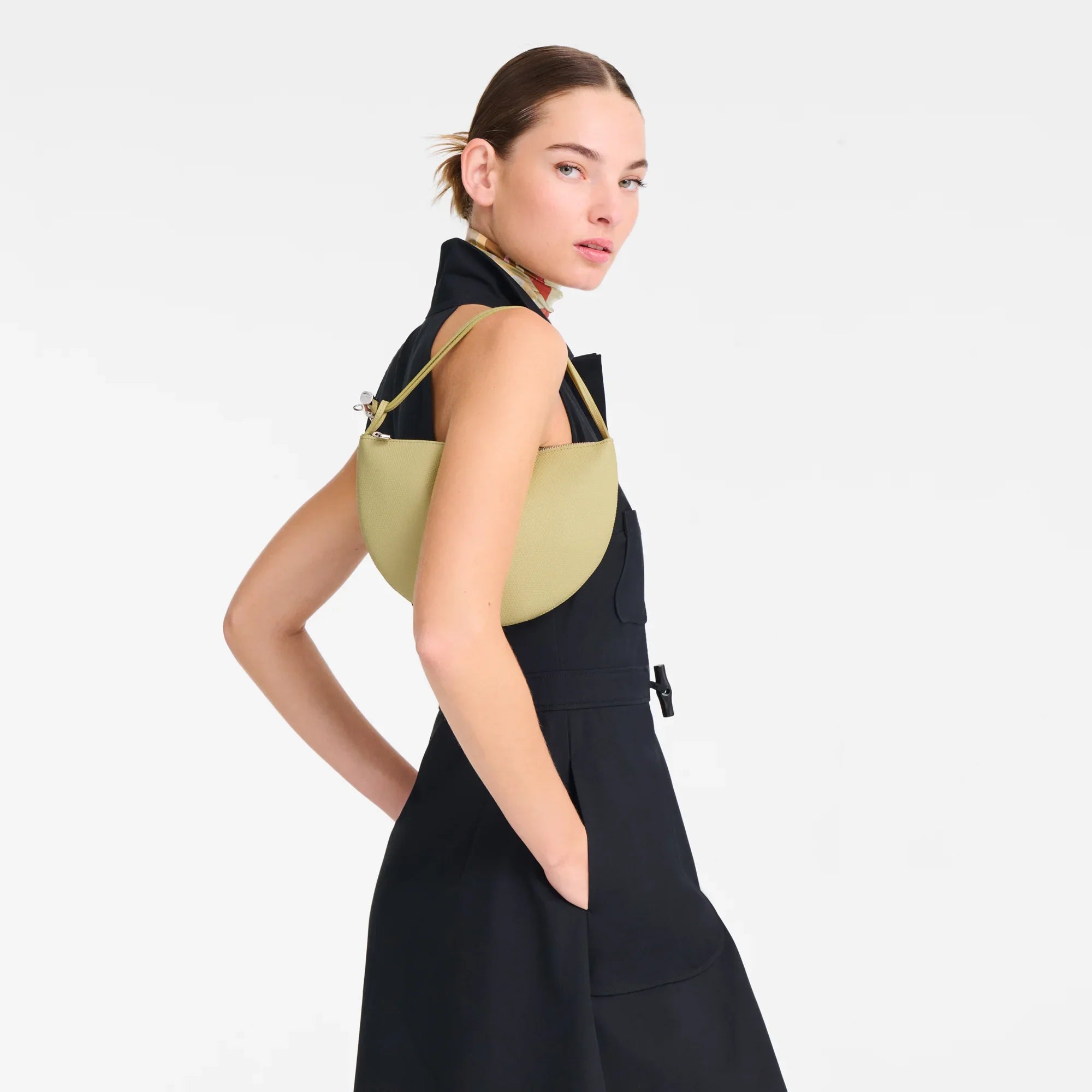 אישה לובשת שמלה שחורה עם תיק כתף אופנתי בז' מבית המותגים CHOZEN