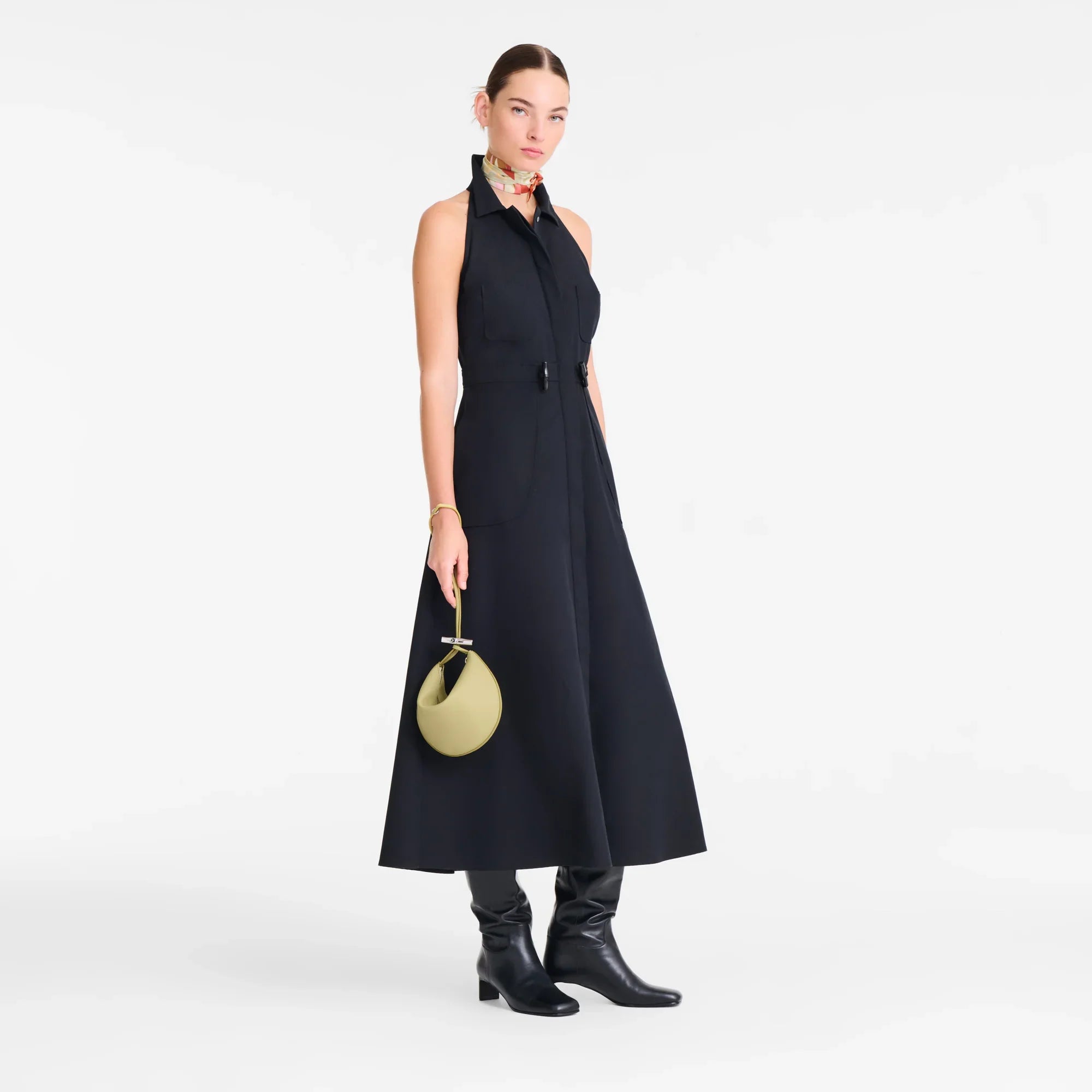 דוגמנית לובשת שמלת מקסי שחורה, מגפיים שחורים וצעיף צבעוני, עם תיק יד עגול, מצולמת בסטודיו. מותגי אופנה ב-CHOZEN