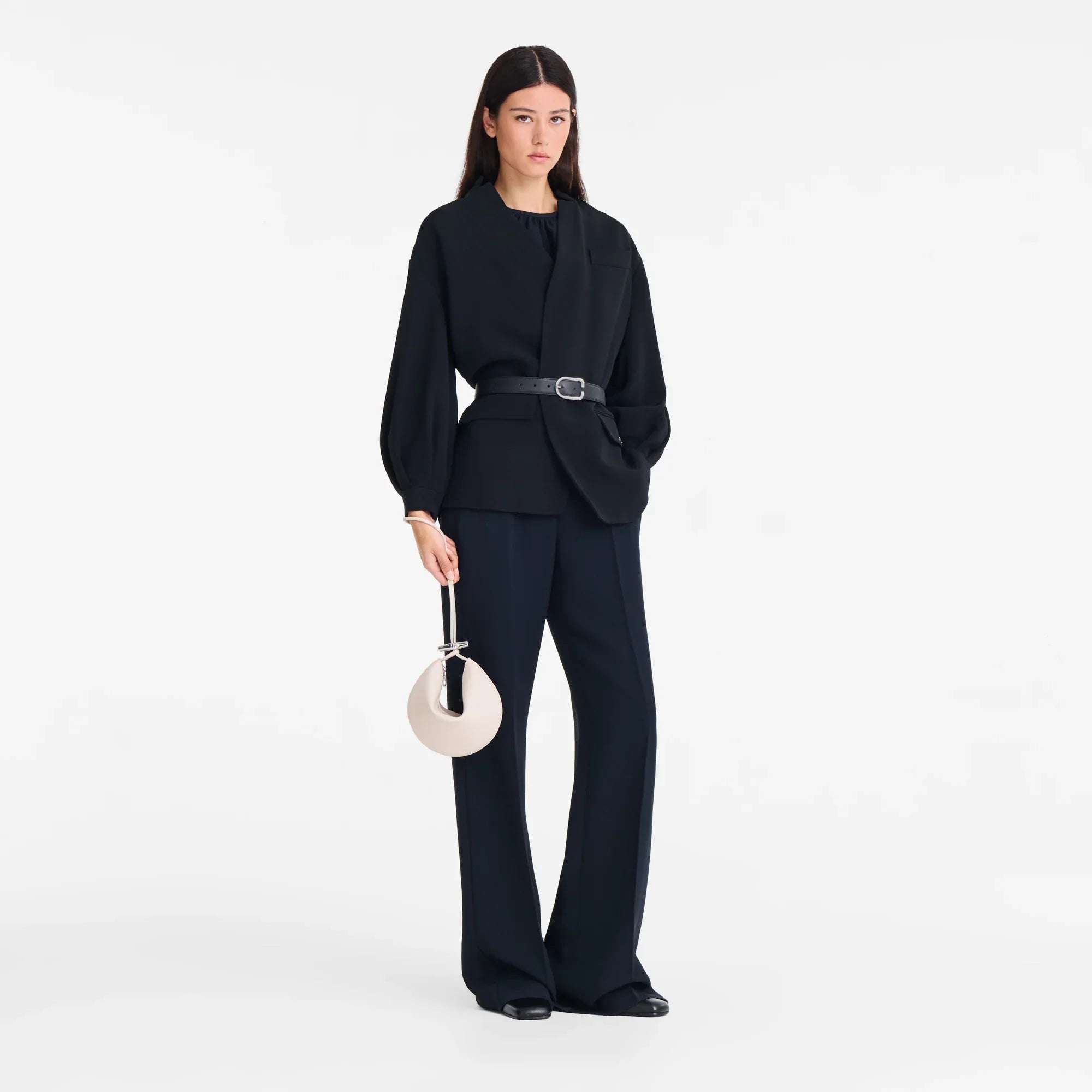 דוגמנית לובשת חליפה שחורה אופנתית עם חגורה, מחזיקה תיק מעוצב, צילום אופנה ל-CHOZEN