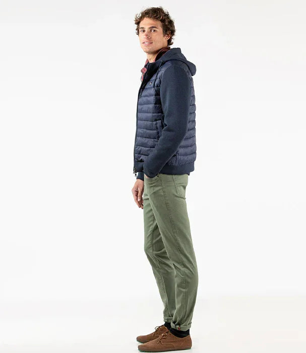 דוגמן לובש וסט פוך כחול כהה, סווטשירט, מכנסיים ירוקים ונעליים חומות על רקע לבן – CHOZEN אופנה לגברים