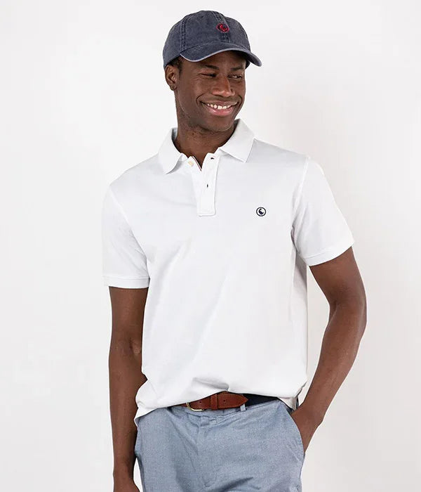 גבר מחייך לובש חולצת פולו לבנה וכובע אפור, אופנת CHOZEN, צילום בסטודיו