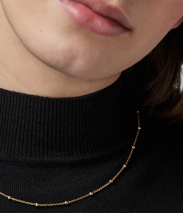 שרשרת זהב עדינה על צוואר אישה, חולצה שחורה, תכשיטים CHOZEN קבוצה אלפא