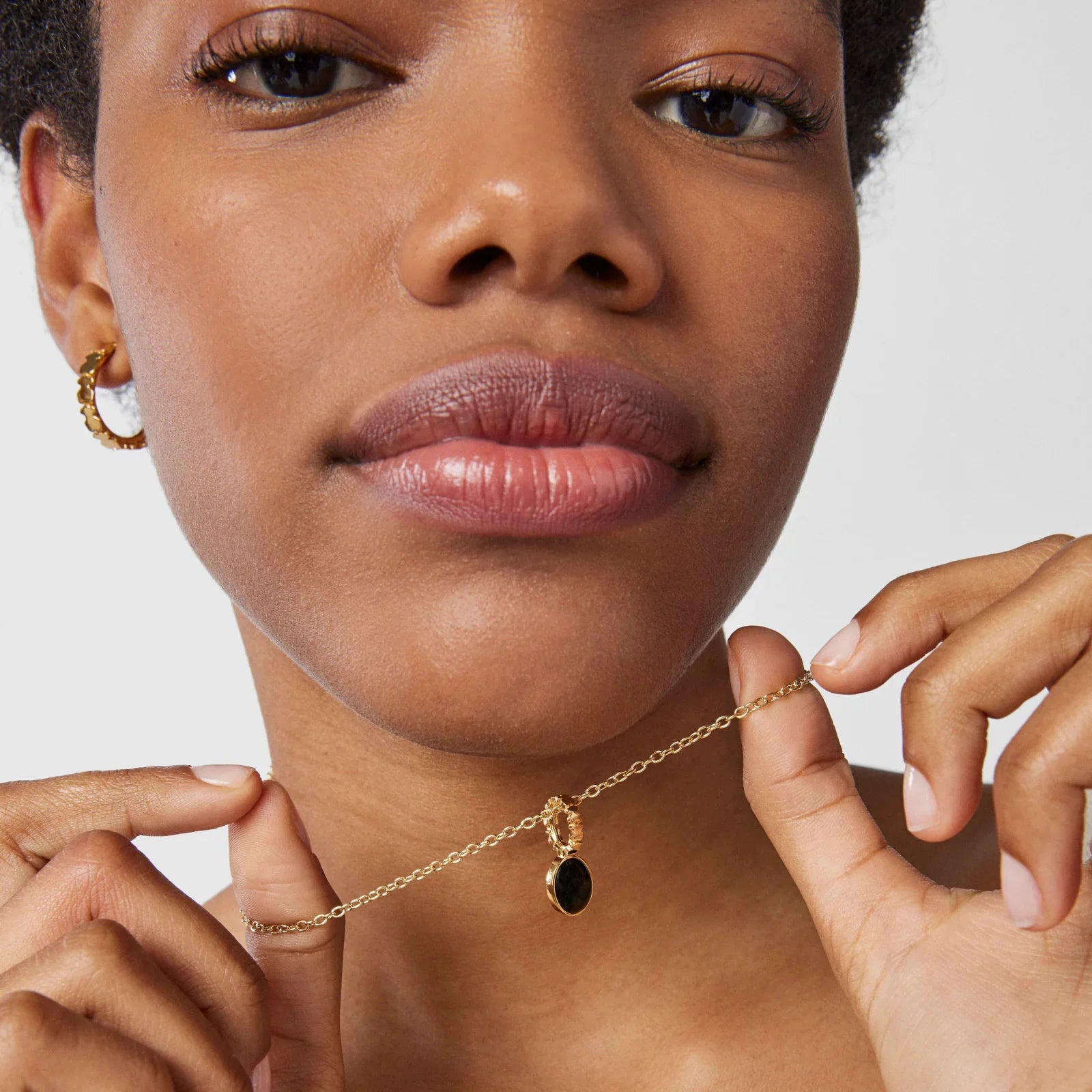 אישה מציגה שרשרת זהב עם תליון שחור, תכשיטי אופנה יוקרתיים מבית CHOZEN
