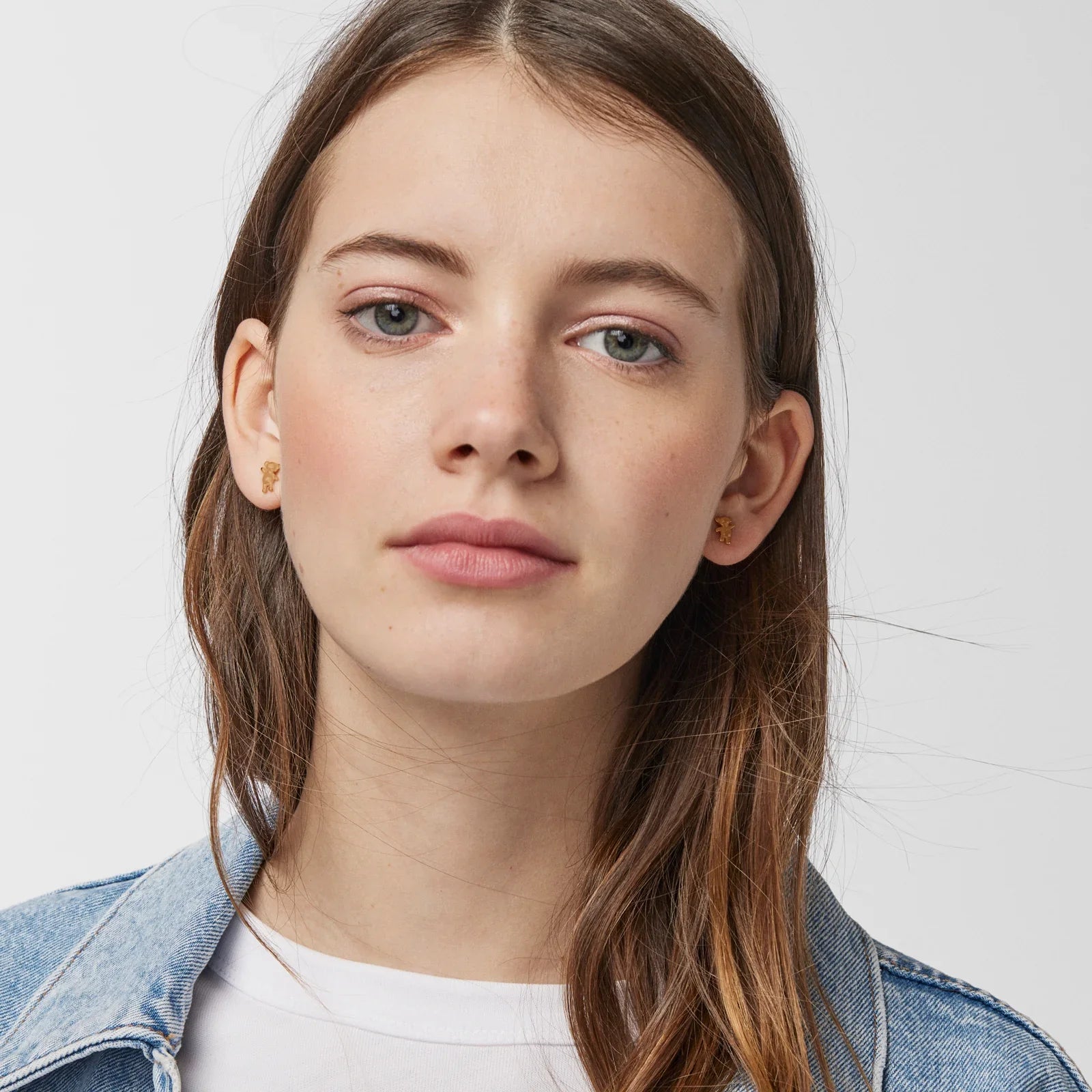 אישה צעירה עונדת עגילי זהב, לבושה ג'ינס, פריים תקריב, CHOZEN מותגים מובילים