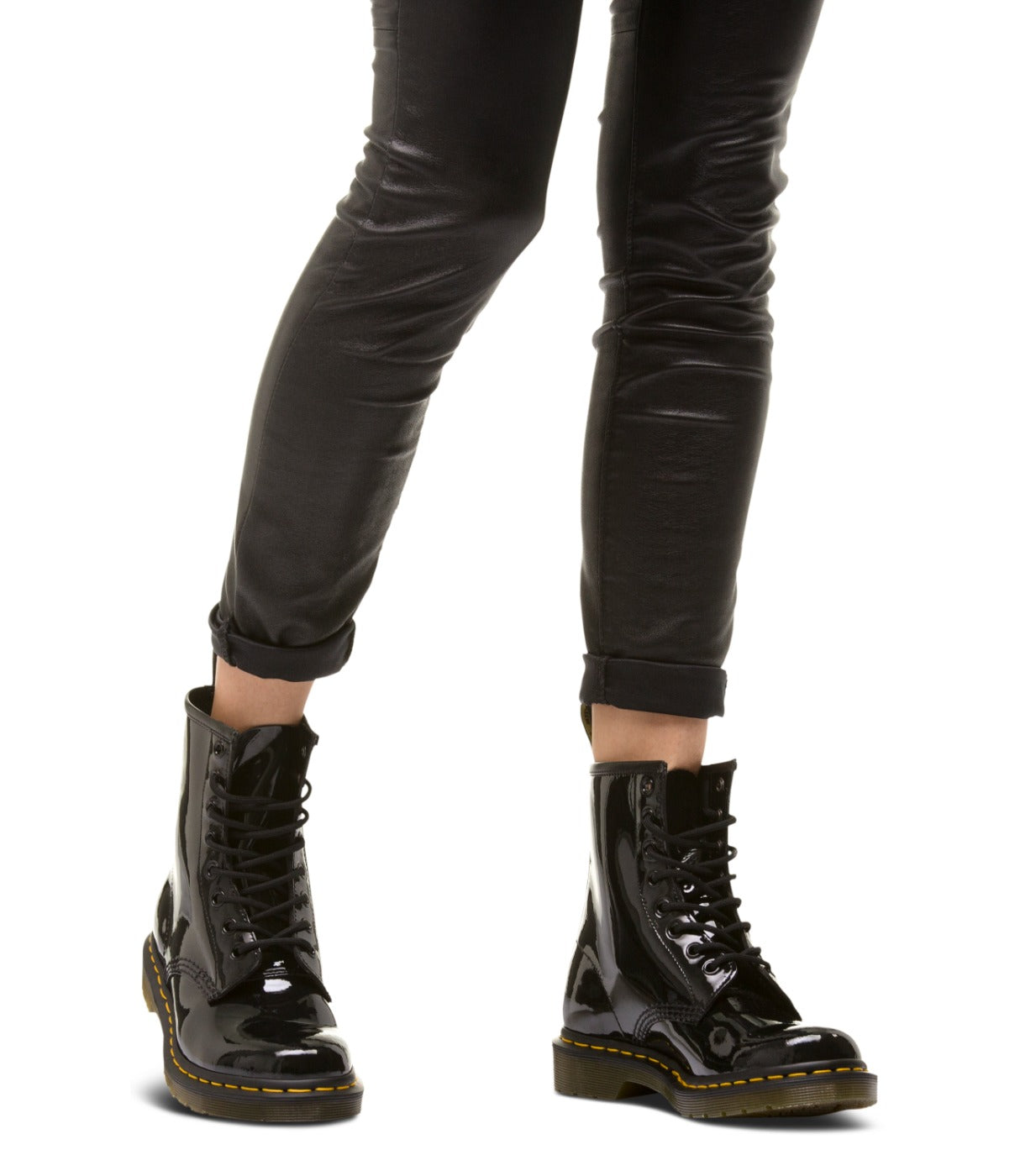 מגפי DR. MARTENS 1460 שחורים לכה מוצגים על רגלי אישה עם מכנסי עור שחורים, מבית CHOZEN