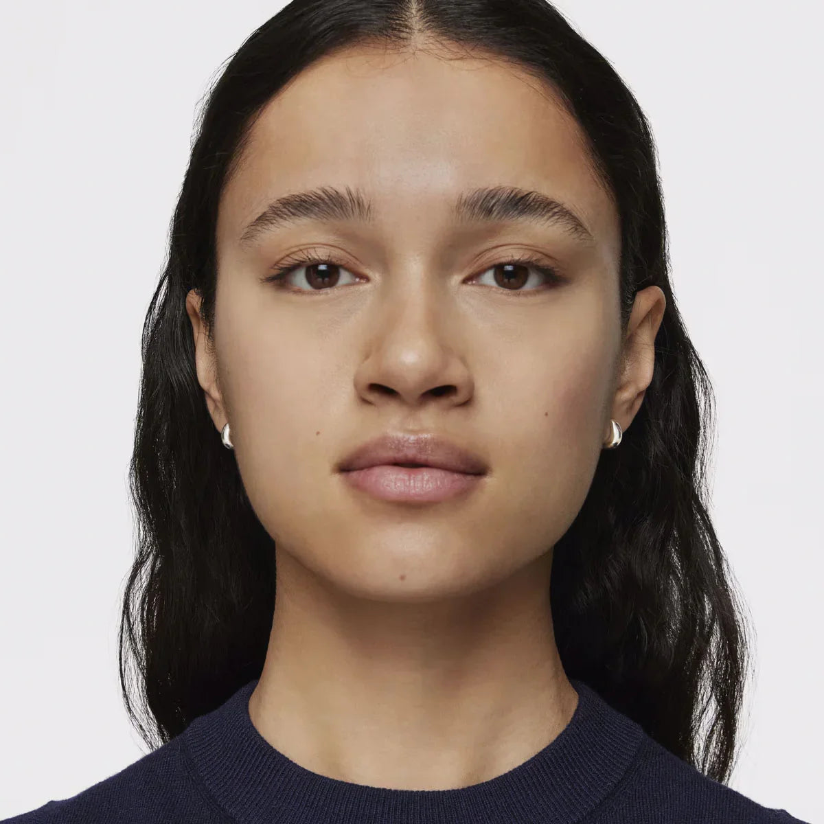 אישה עם שיער כהה ארוך, עונדת עגילי כסף, צילום תקריב CHOZEN