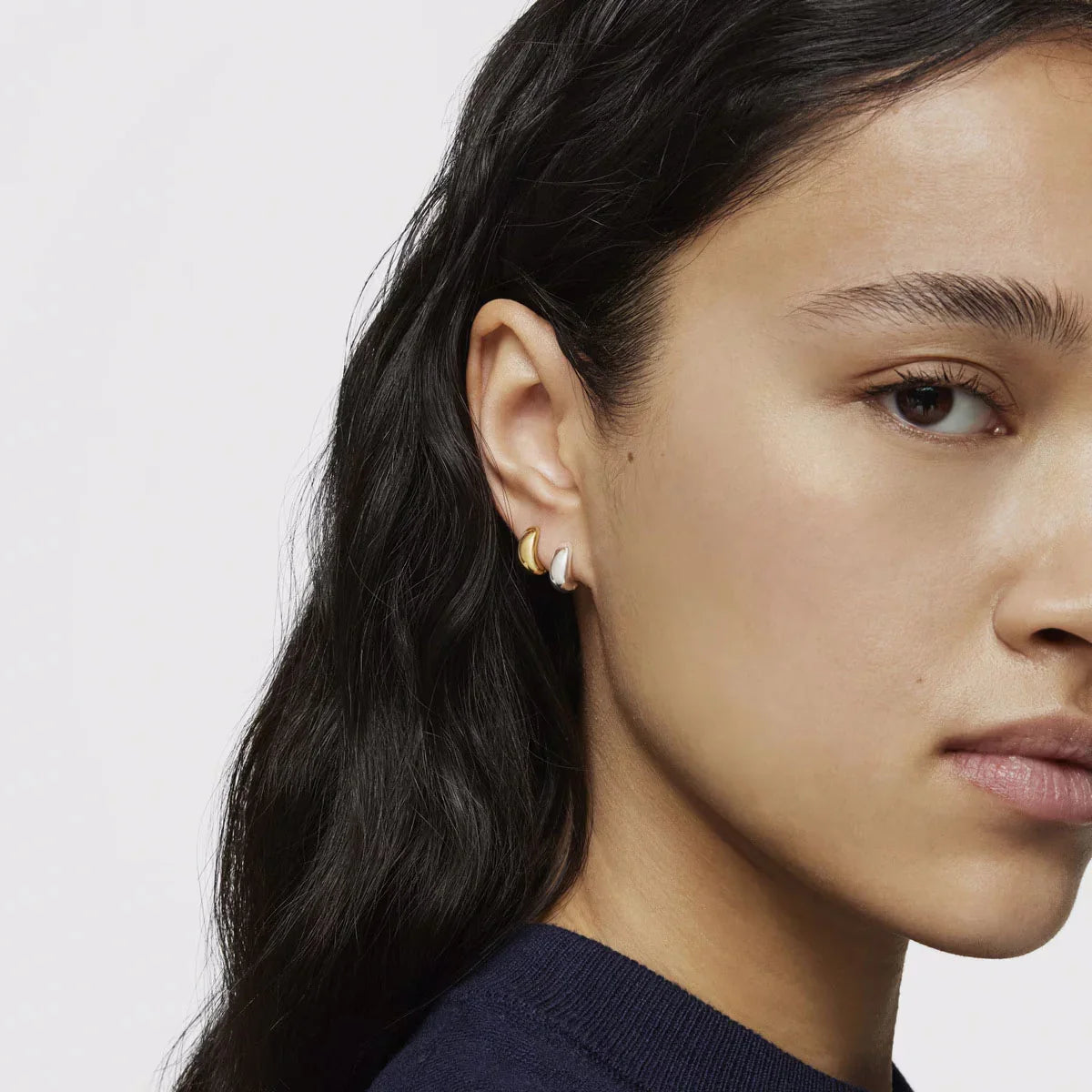 אישה עם שיער כהה עונדת עגילי חישוק זהב וכסף, צילום תקריב, CHOZEN מותגים מובילים