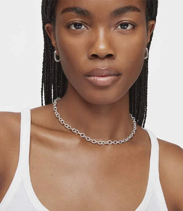 אישה עם שרשרת כסף אופנתית של CHOZEN, עגילים, וגופייה לבנה, צילום תקריב על רקע לבן