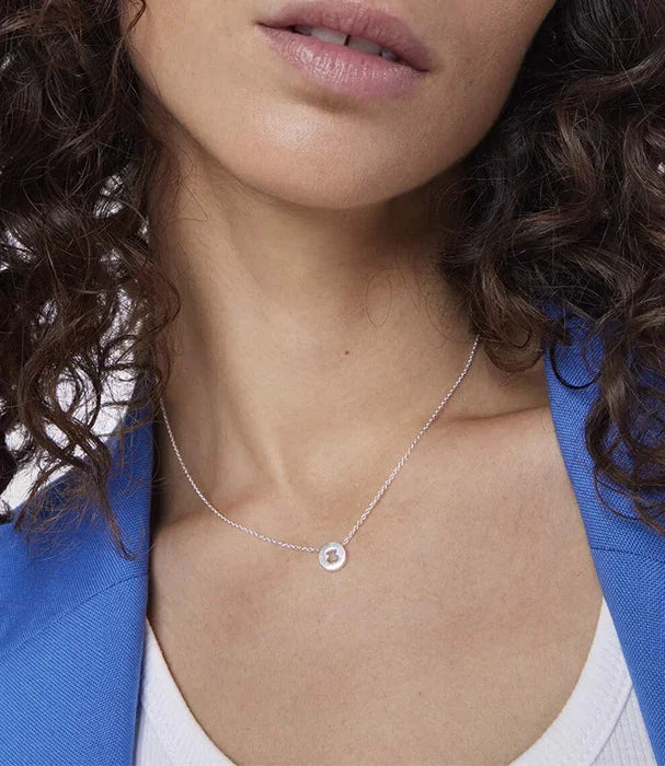 שרשרת כסף עדינה ותליון עגול על דוגמנית עם שיער מתולתל, בלייזר כחול, מתוך CHOZEN
