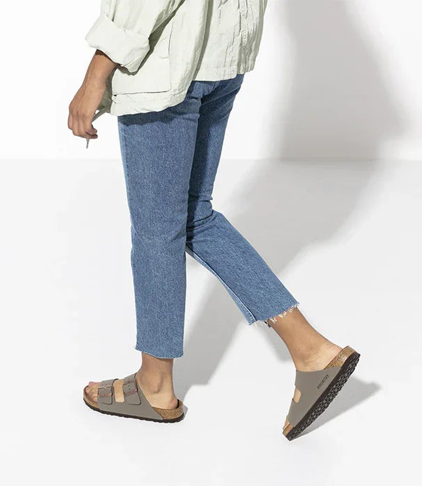 אדם לובש סנדלים חומים של BIRKENSTOCK, ג'ינס כחול וחולצה בהירה, מצולם על רקע לבן, CHOZEN