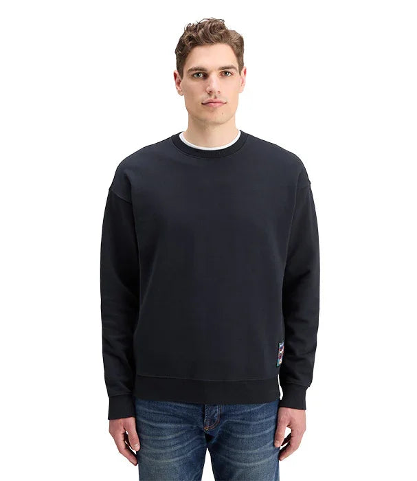 גבר לובש סווטשירט שחור אופנתי וג׳ינס כחול, צילום אולפן לקולקציית CHOZEN מותגים מובילים