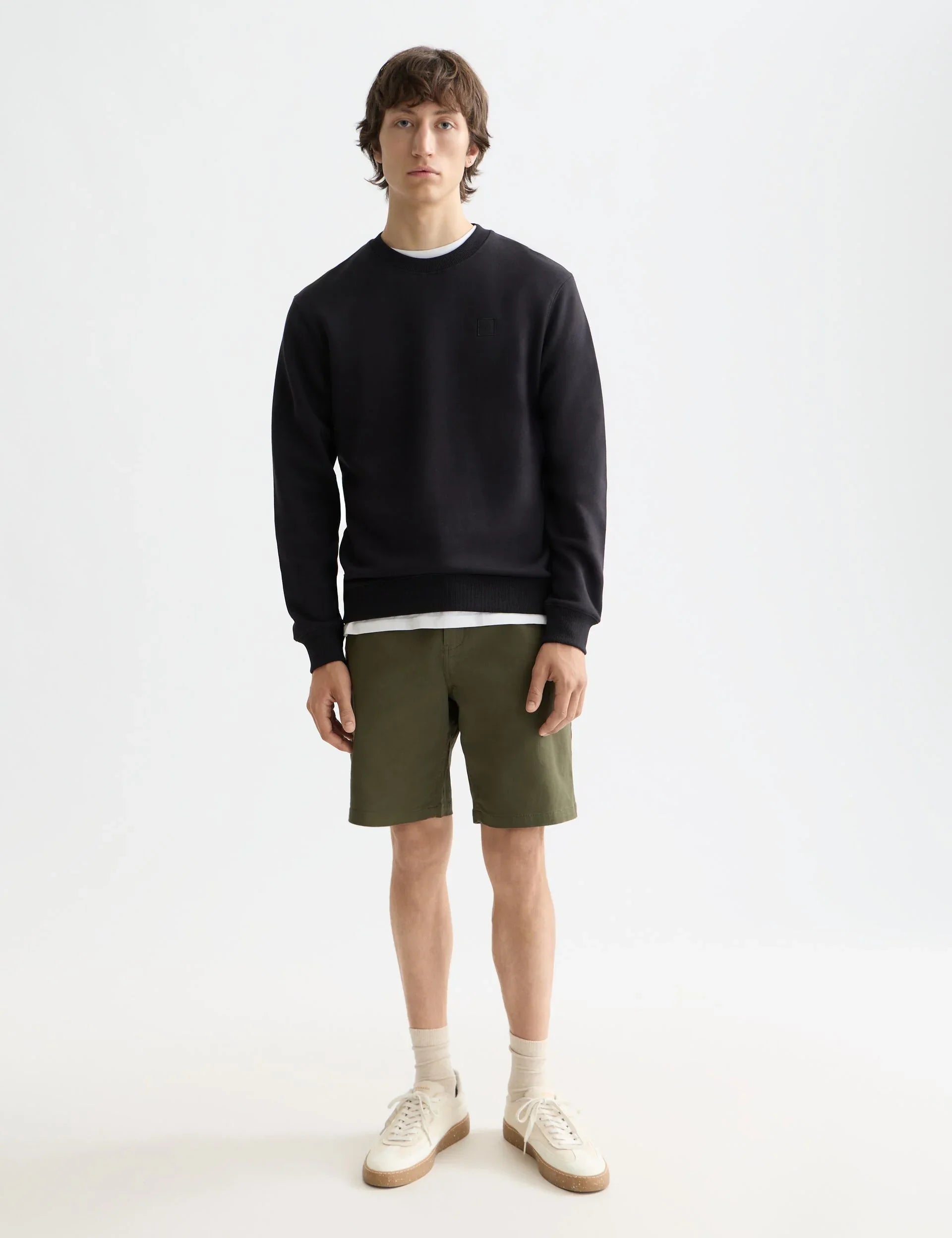 דגם גבר לובש סווטשירט שחור, מכנסיים קצרים ירוקים ונעלי סניקרס, אופנה CHOZEN