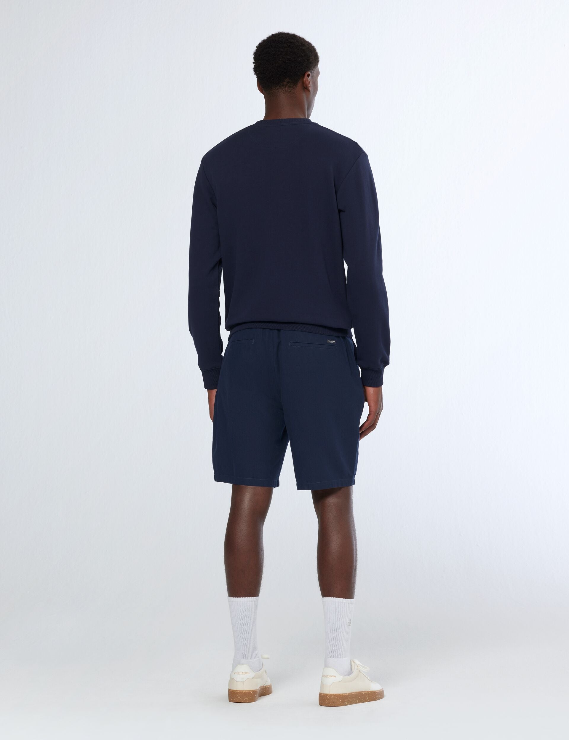 גבר עם סווטשירט כחול כהה ומכנסי שורטס, אופנה מודרנית CHOZEN, צילום על רקע לבן