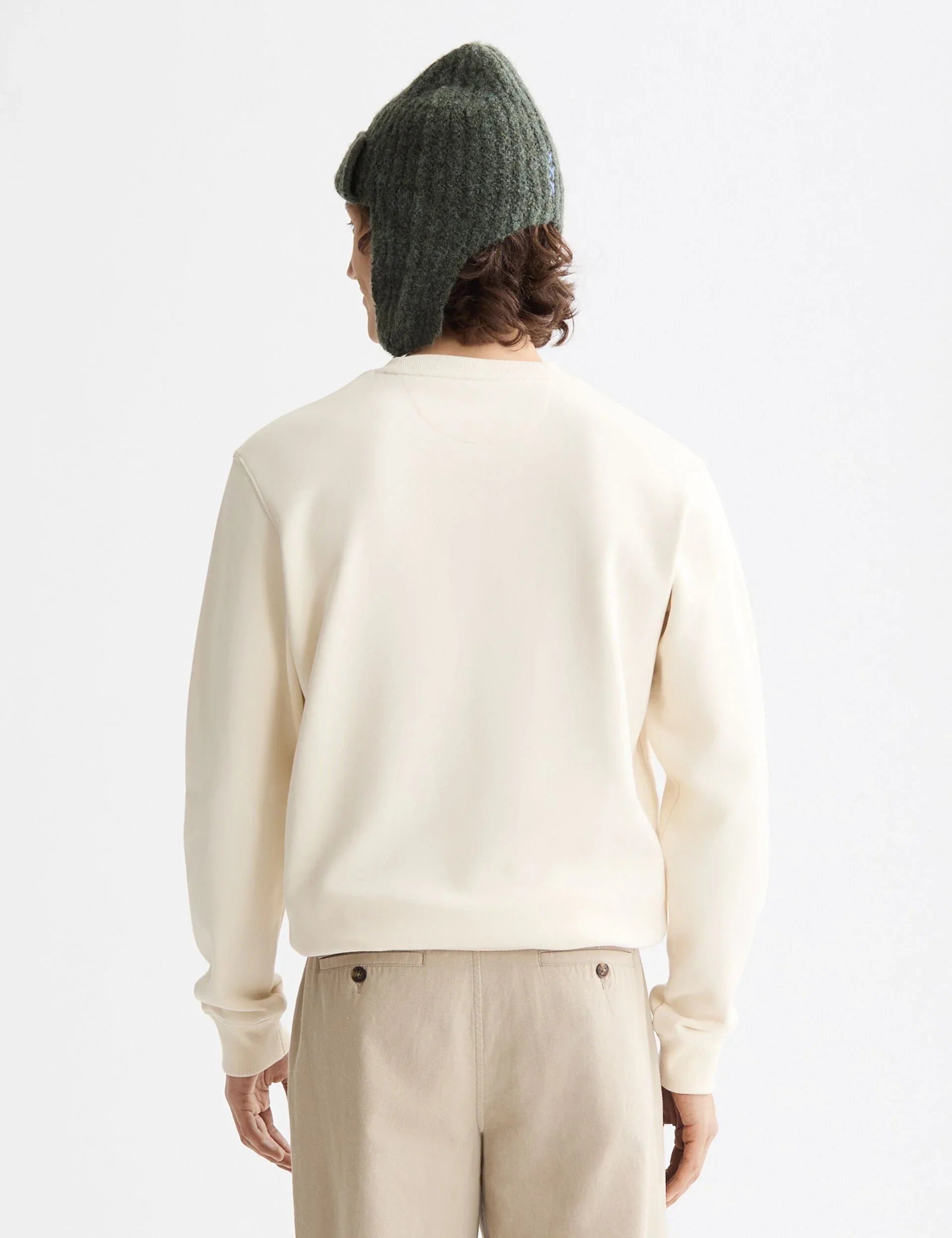 אדם בחולצה בהירה וכובע ירוק מצמר, מבט מאחור, צילום אופנה ל-CHOZEN