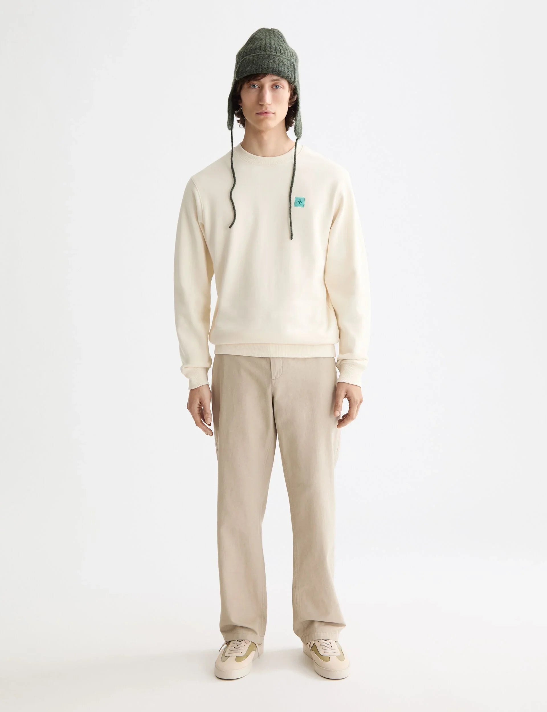 דגם גבר בלבוש קז'ואל אופנתי מבית CHOZEN, סווטשרט שמנת וכובע חורף ירוק