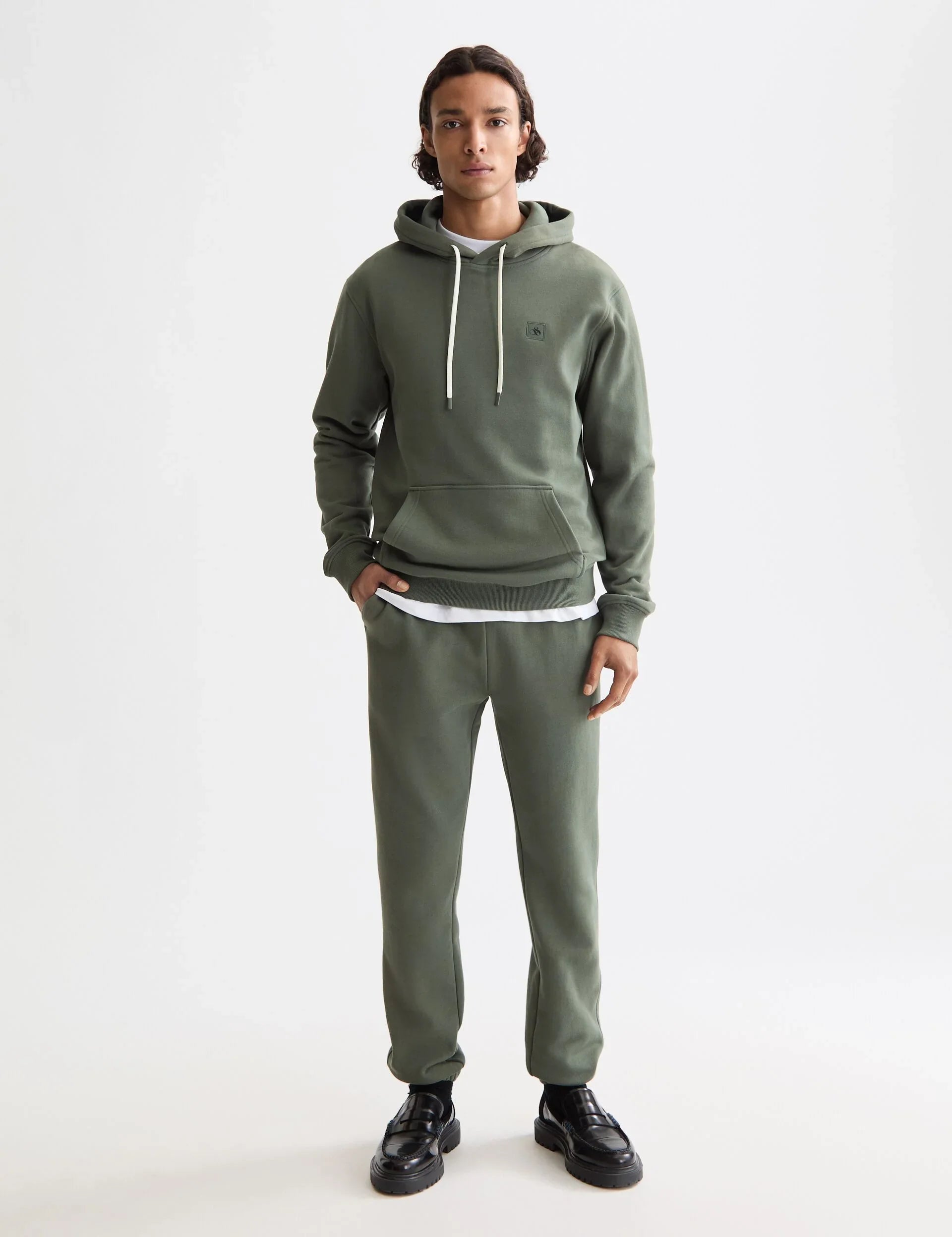 דגם גבר לובש סט קפוצ'ון ומכנסיים ירוקים של CHOZEN רקע לבן, אופנה איכותית