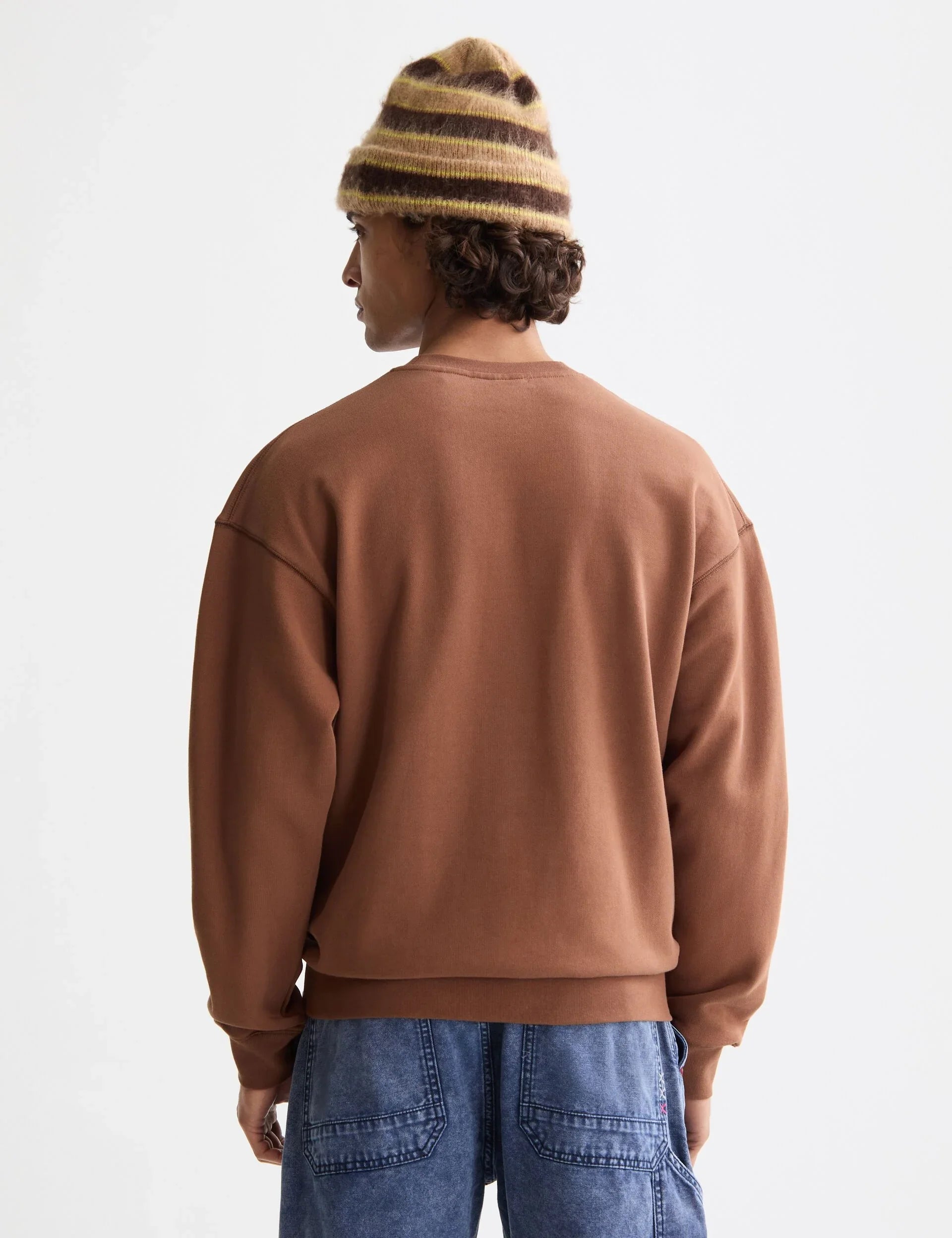 גבר עם סווטשירט חום, מכנסי ג'ינס וכובע פסים, אופנה טרנדית CHOZEN