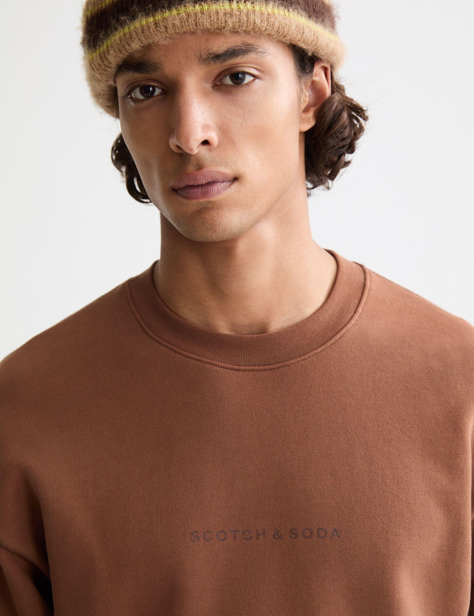 דוגמן לובש סווטשרט חום של סקוץ' אנד סודה וכובע צמר, קולקציית מותגים ב-CHOZEN