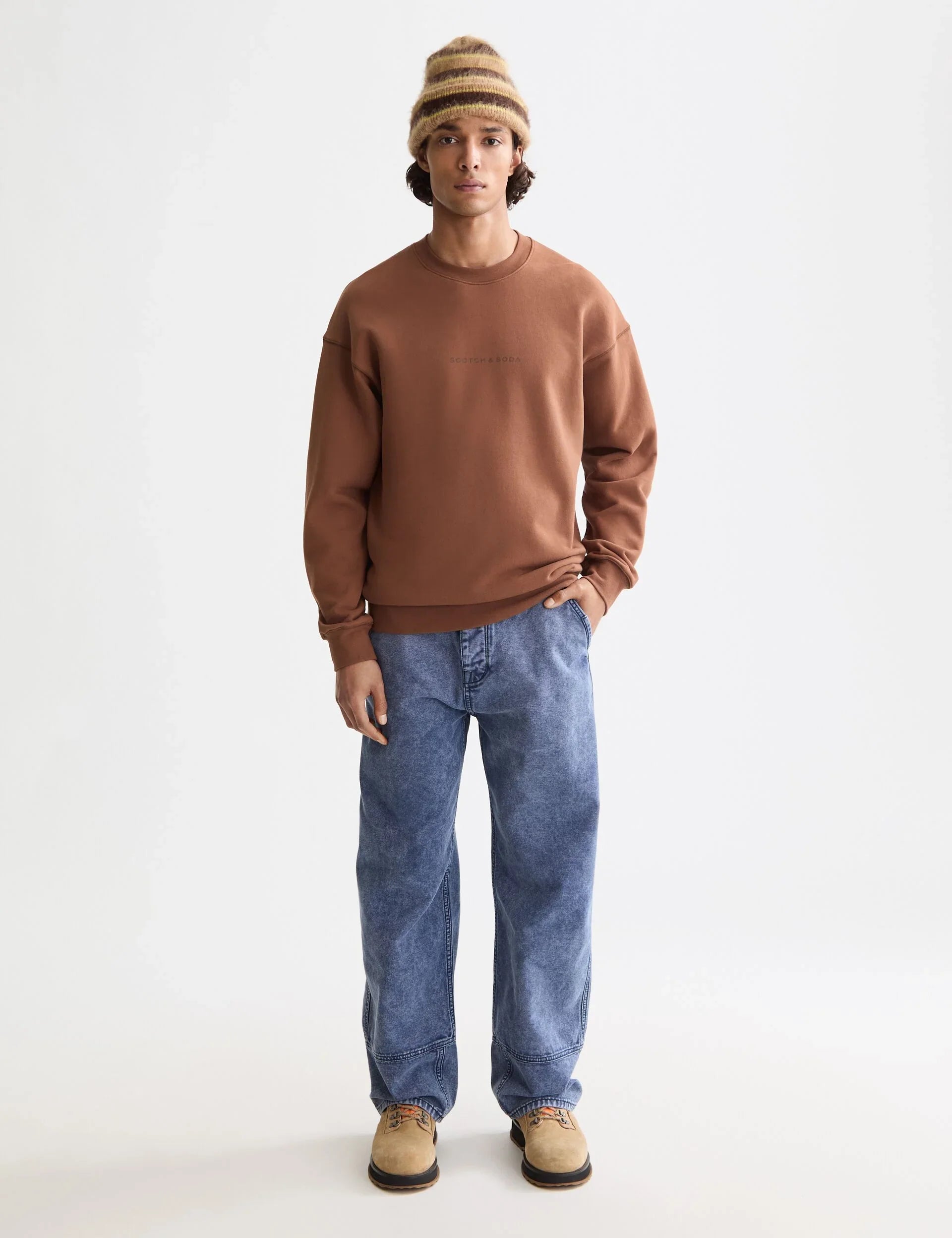 דוגמן צעיר לובש סווטשירט חום, ג׳ינס כחול וכובע צמר, אופנת גברים, CHOZEN מותגים מובילים