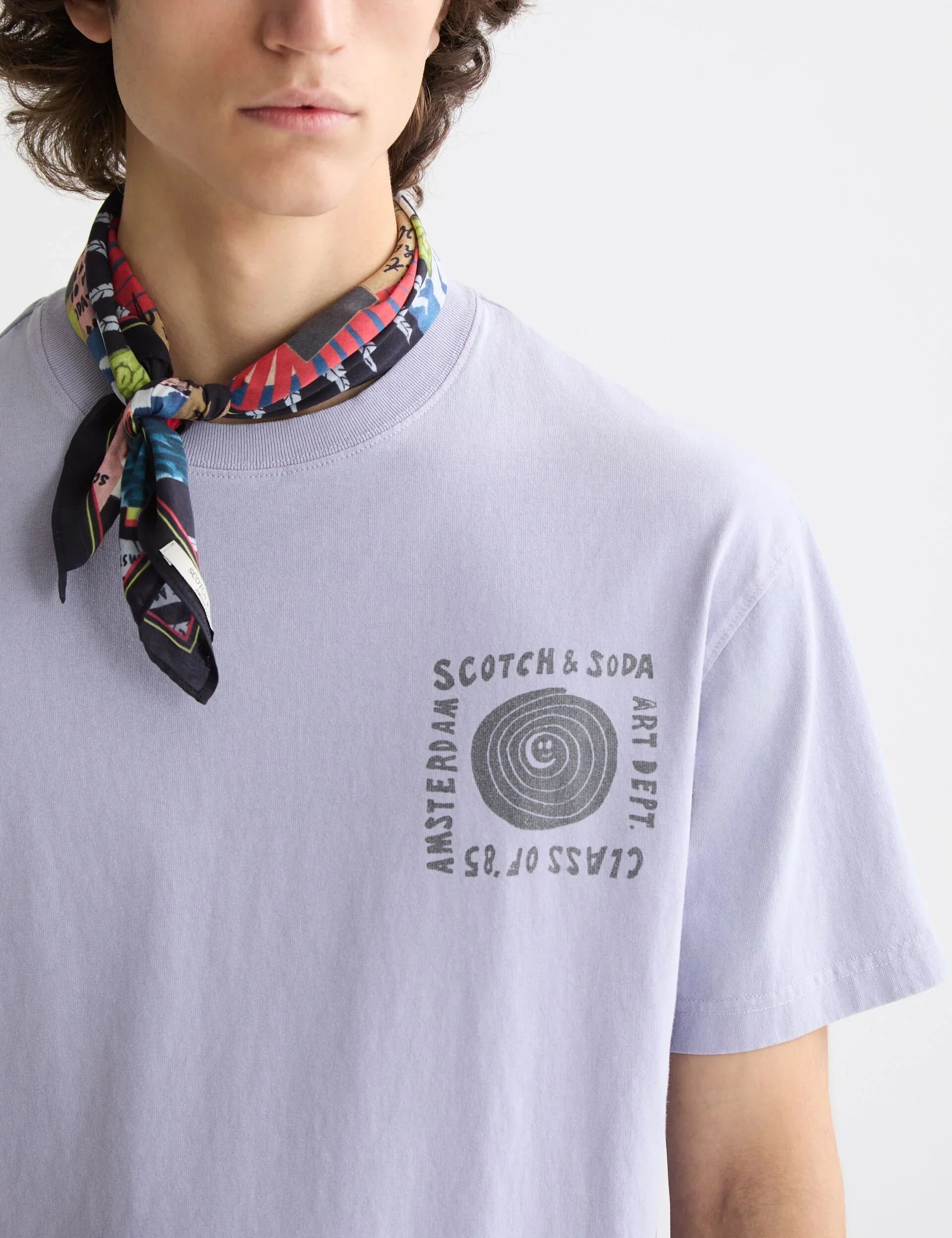 גבר לובש חולצת טי סגולה עם הדפס Scotch & Soda וצעיף צבעוני, אופנה יוקרתית ב-CHOZEN