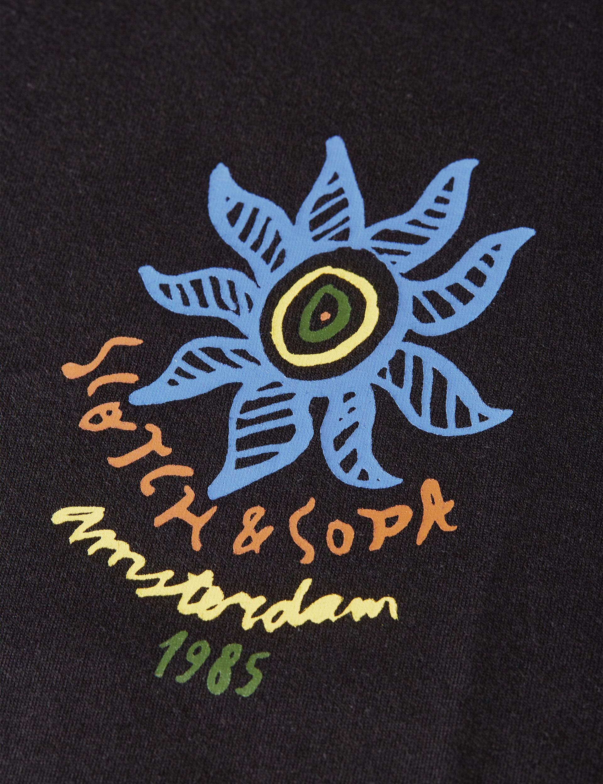 הדפס צבעוני של פרח ודימוי גרפי עם הטקסט Scotch & Soda Amsterdam 1985 על חולצה שחורה מבית CHOZEN