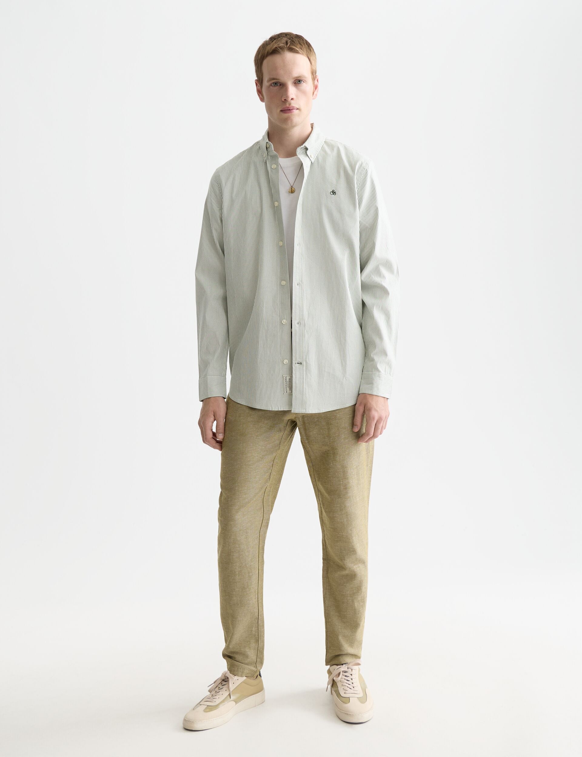 דגם גבר לובש חולצה מכופתרת ירוקה ומכנסיים בז׳, אופנת גברים CHOZEN