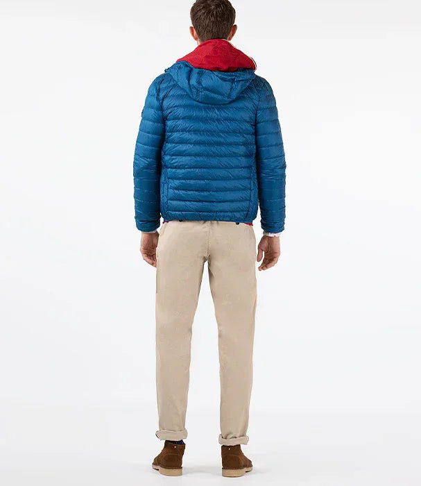 גבר לובש מעיל פוך כחול עם קפוצ'ון אדום, מכנסיים בז', נעלי זמש חומות, רקע לבן, CHOZEN