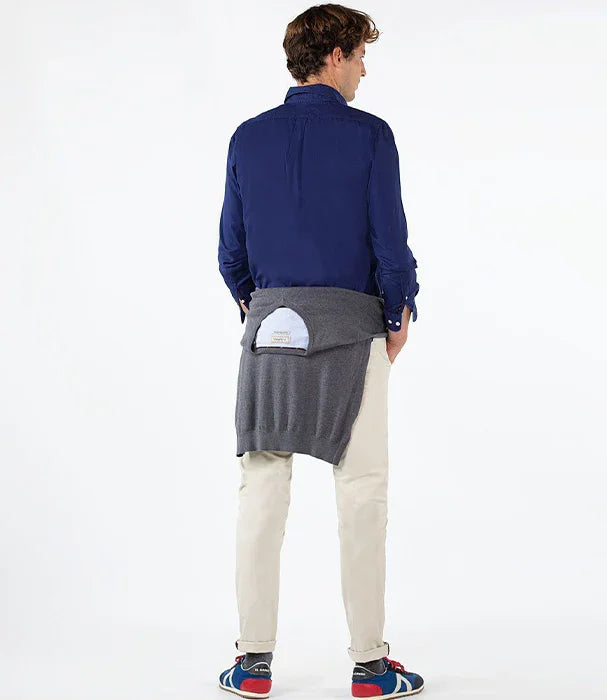 גבר בלבוש קז'ואל עם חולצה כחולה, מכנסיים בהירים וסוודר אפור של CHOZEN קשור סביב המותניים