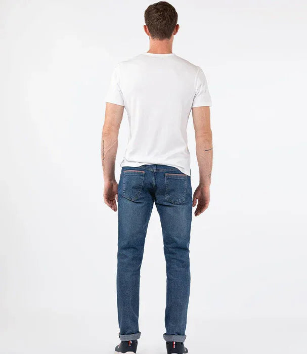 גבר לובש ג'ינס כחול וחולצת טי לבנה עומד עם גב למצלמה, צילום אופנה CHOZEN