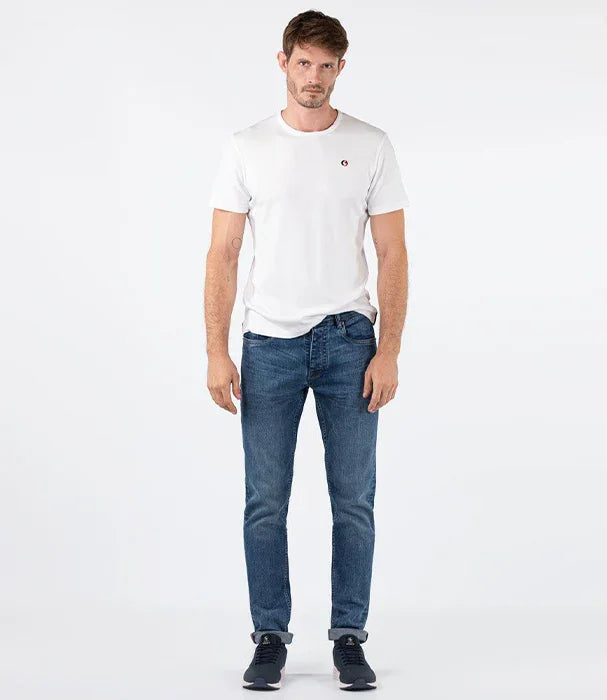 גבר לובש חולצה לבנה של CHOZEN וג'ינס כחול, עומד על רקע לבן, אופנה לגברים