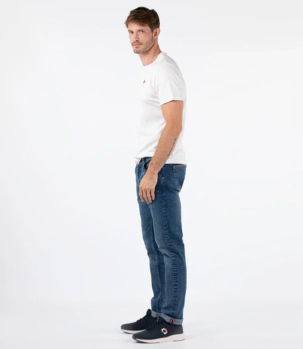 גבר מדגמן ג'ינס כחול, חולצת טי לבנה ונעלי סניקרס שחורות על רקע לבן לאתר CHOZEN