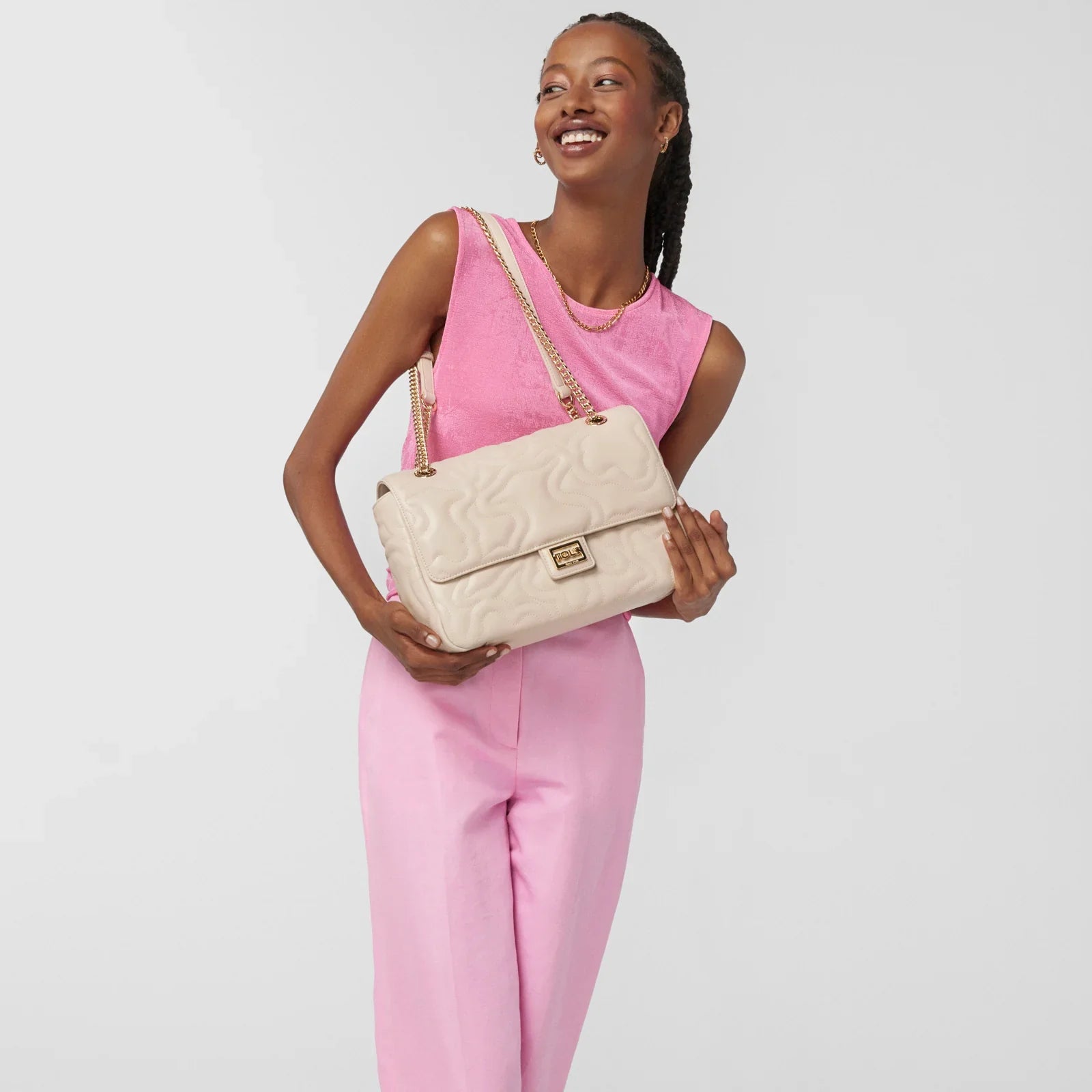 אישה עם תיק צד מעוצב שמנת מבית CHOZEN, לובשת חולצה ומכנסיים ורודים