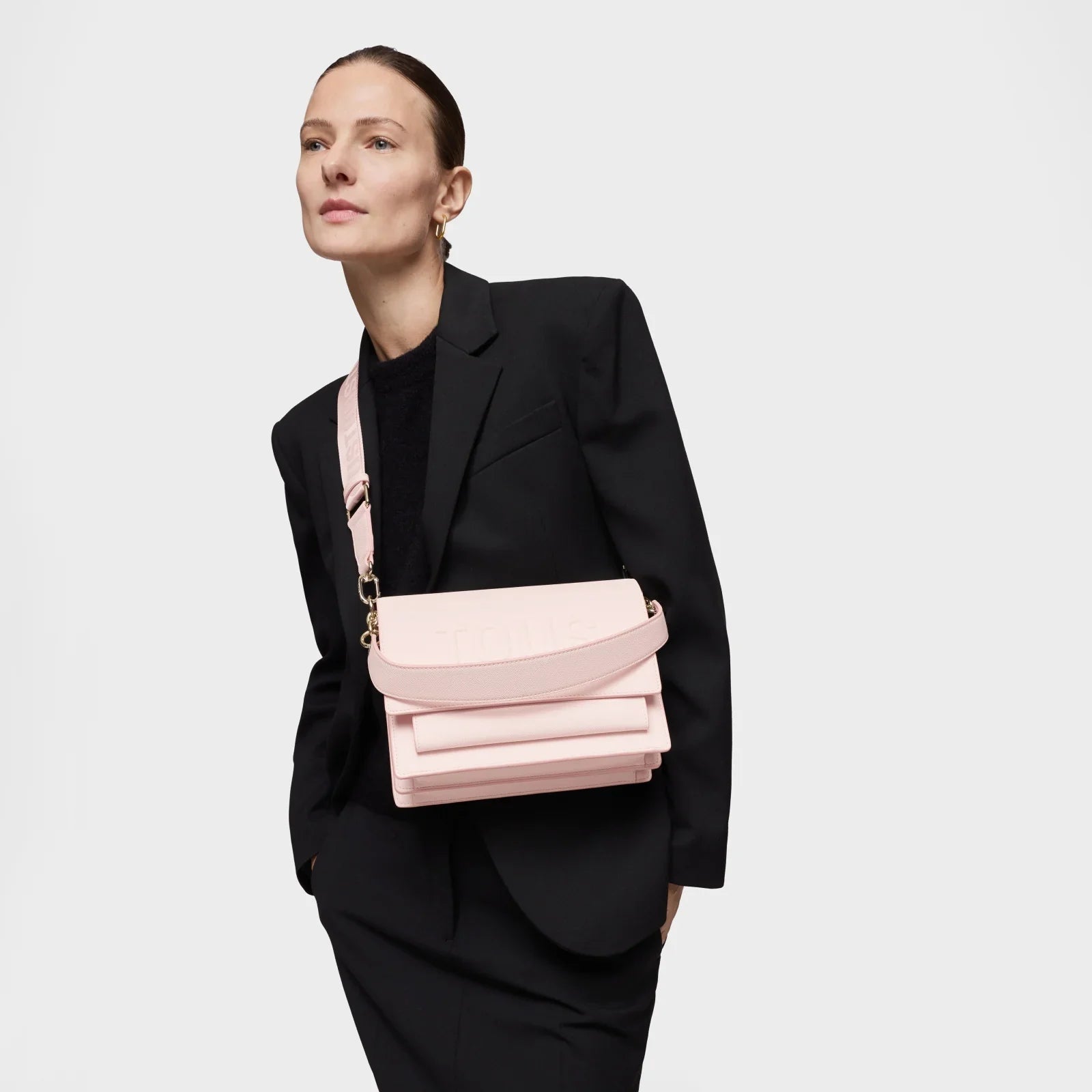 אישה לובשת חליפה שחורה אופנתית עם תיק צד ורוד מבית CHOZEN מותגים מובילים