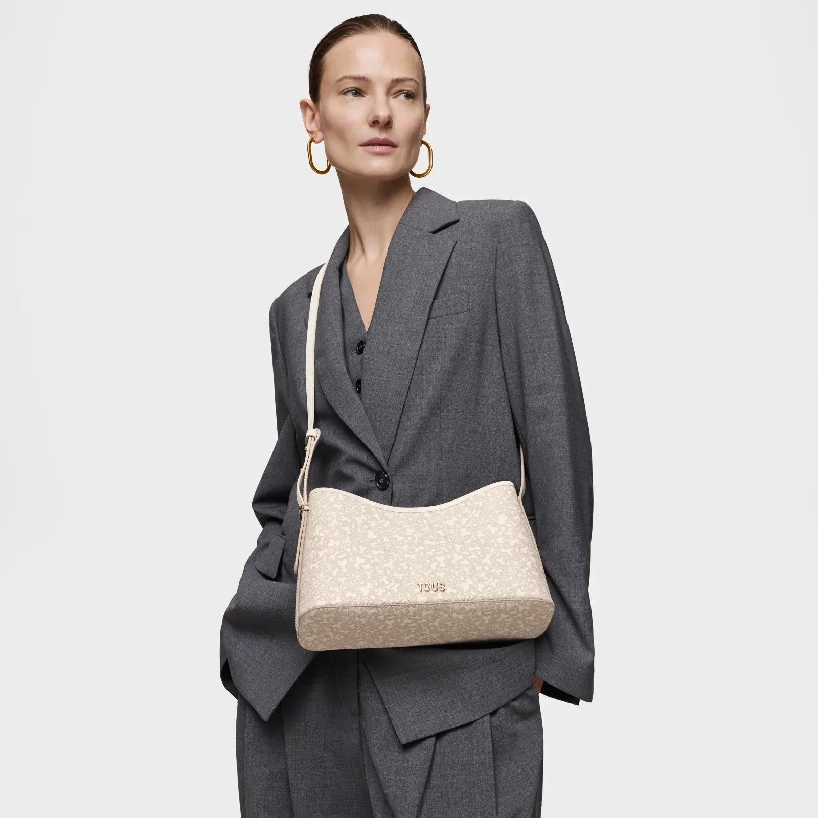 דוגמנית בחליפת מחויטת אפורה עם תיק כתף אופנתי בצבע בז', מותג TOUS, קולקציית CHOZEN