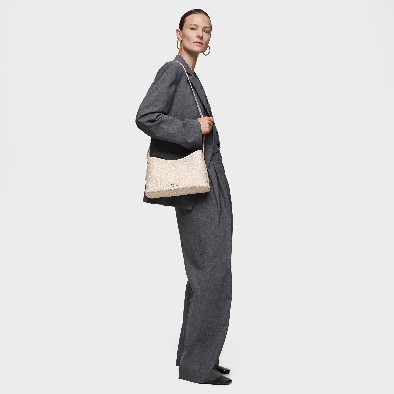 אישה בחליפת עסקים אפורה נושאת תיק צד של TOUS, צילום אופנה ל-CHOZEN מותגים בינלאומיים