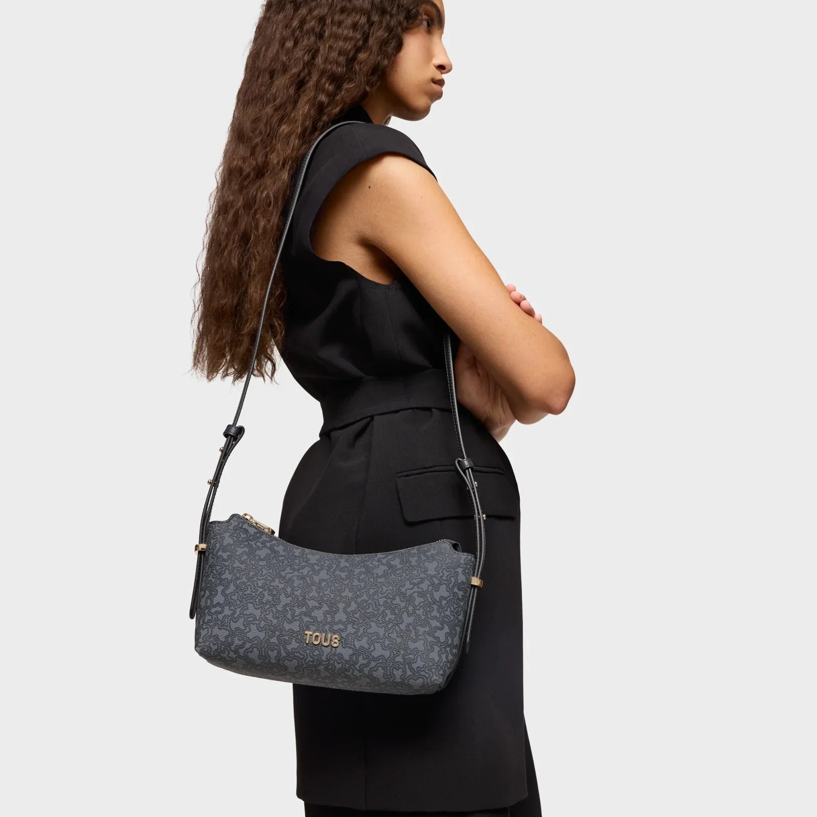 אישה לובשת שמלה שחורה עם תיק מותג TOUS אפור, אופנה יוקרתית מקבוצת אלפא