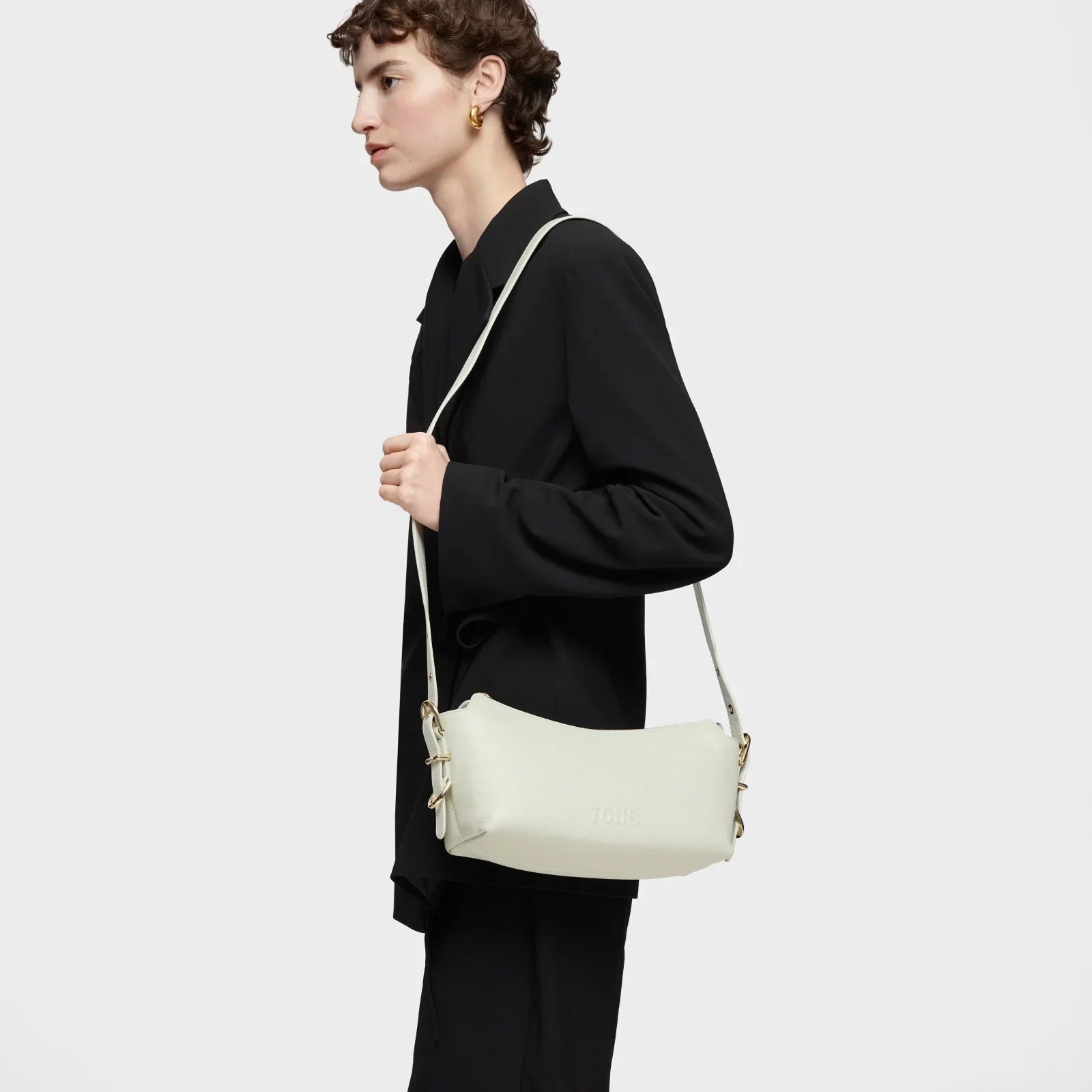 אישה לובשת חליפה שחורה עם תיק צד לבן של TOUS, צילום מוצר אופנה CHOZEN מותגים מובילים