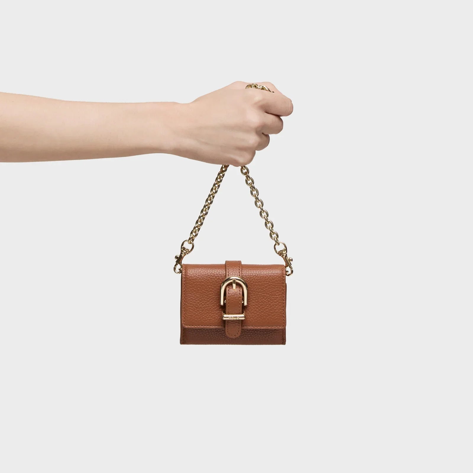 תיק קטן מעור חום עם שרשרת זהב, מוחזק ביד, קמפיין מותגים CHOZEN